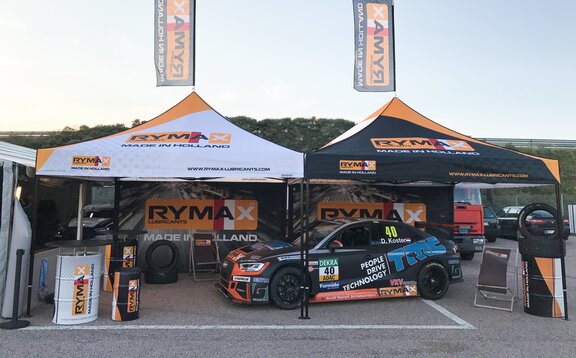 Gazebo racing & gazebo paddock Rymax Gazebo da corsa completamente personalizzato in occasione di un evento sulla strada. E' completamente stampato. Sotto c'è una macchina. La squadra corse appartiene a Rymax.