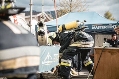 Gazebo pieghevole per intervento dei vigili del fuoco. CI sono delle attrezzature dei vigili del fuoco e un gazebo stampato MASTERTENT.
