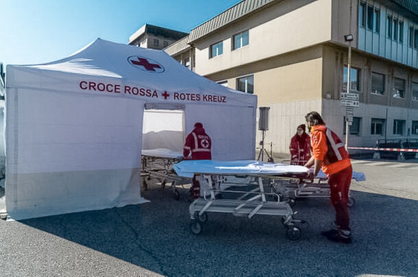 The Red Cross staff carries the corona patient to the rescue tent. The Rescue Kit tent is white. 