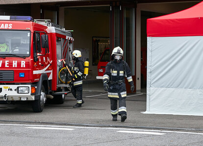 Feuerwehrmann mit Atemschutzgerät geht zwischen Auto und dem Kit Rescue vorbei.