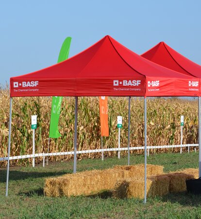 Roter Faltpavillon steht auf dem Feld. Darunter befinden sich einige Strohballen.