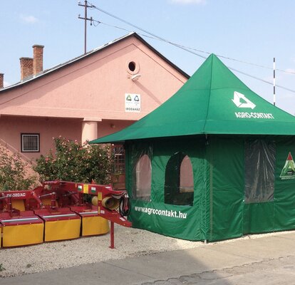 Gazebo pieghevole per agricoltura con finestre. Vicino ci sono delle macchine agricole.