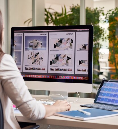 Grafikmitarbeiterin sitzt am Computer und erstellt einen Faltpavillon für einen Kunden.