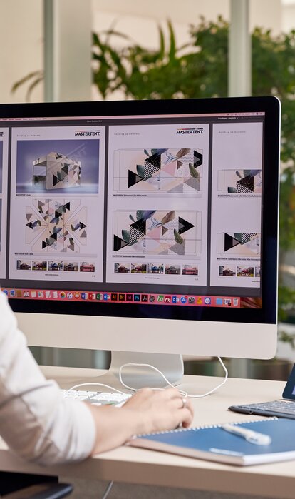 A graphic employee is sitting in front of the computer. She is designing a gazebo for a customer. 