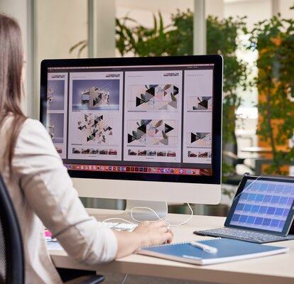 A graphic employee is sitting in front of the computer. She is designing a gazebo for a customer. 