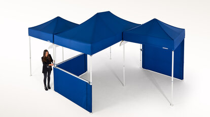 Una signora unisce più gazebo pieghevoli e crea un piccolo parco di gazebo pieghevoli.