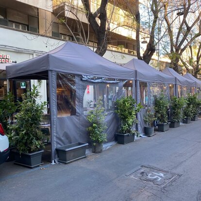 Elegant and modern grey 4x2 m folding gazebo with side walls with windows. Row of gazebos used in the outdoor area of the local bar/restaurant Sazi e Sani on the city streets