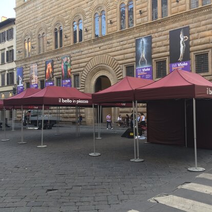 Gazebo pieghevole bordeaux 4x2 m con parete laterale intera e pesi per il fissaggio. Il gazebo è personalizzato con logo "il bello in piazza" ed è utilizzato da un Comune per un evento culturale in città