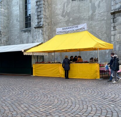 Gazebo 6x3 giallo con tettoia e parete laterale a mezza altezza con banner personalizzato Mastertent in uno scorcio di Bressanone, Italia