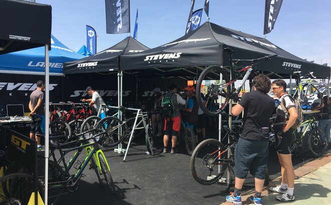Advertising gazebos with roof flags from MASTERTENT at a cycling event.