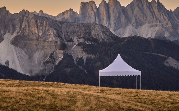 Il gazebo bianco a pagoda si erge sulla montagna. Alle sue spalle si estende una catena montuosa da sogno nel tramonto.