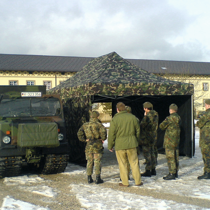 Cort militar cu părți laterale pe o piață înzăpezită în fața unei cazărmi. În fața acestuia stau mai mulți soldați.