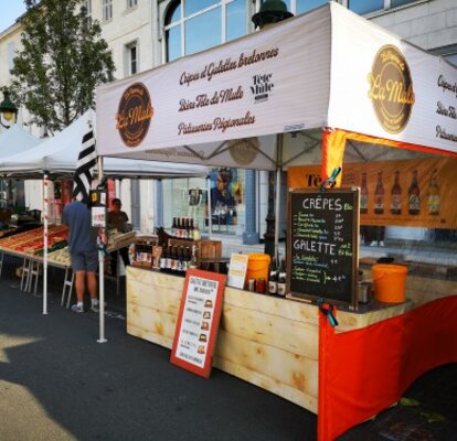 A street food tent with printed roof with the logo La Mule. Additionally equipped with a red side wall with panoramic window. Next to it on the left is another sales stand. 