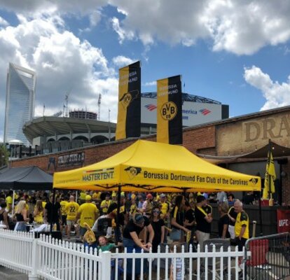 Ein gelber Faltpavillon des BVB Borussia Dortmund Fan Clubs steht dient als Unterstand für viele Fans. 