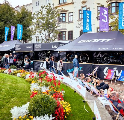 A képen két lapos tetejű, összecsukható pavilon és két csúcsos tetejű, összecsukható pavilon látható. A tetőn zászlók láthatóak. Minden összecsukható pavilonban van pult és személyre szabott.