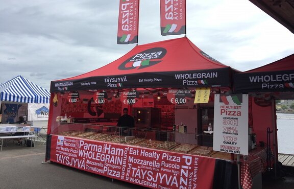 The red folding tent is used as a pizza stand. Pizza slices are sold under the folding tent. There are 2 flags on the roof.