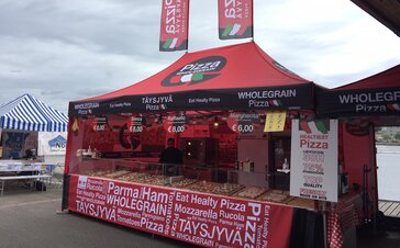 The red folding tent is used as a pizza stand. Pizza slices are sold under the folding tent. There are 2 flags on the roof.