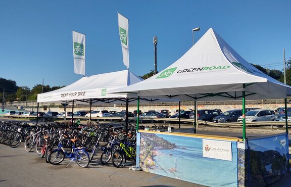 The two white tents from the bicycle rental are outdoors. All the bicycles are underneath.