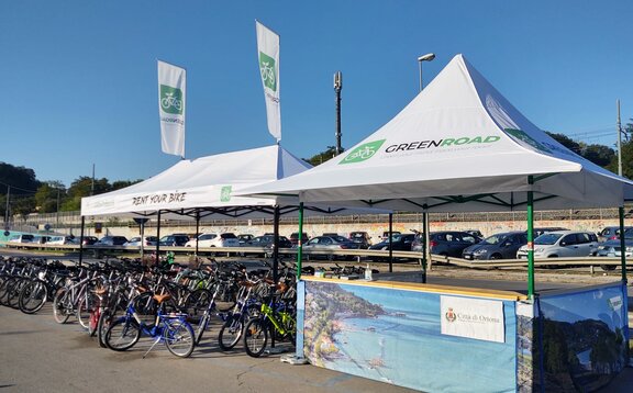 The two white tents from the bicycle rental are outdoors. All the bicycles are underneath.