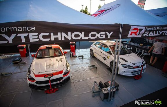 There are 2 racing cars under the RT Rally Technology racing tent. The folding tents serve as a workshop.