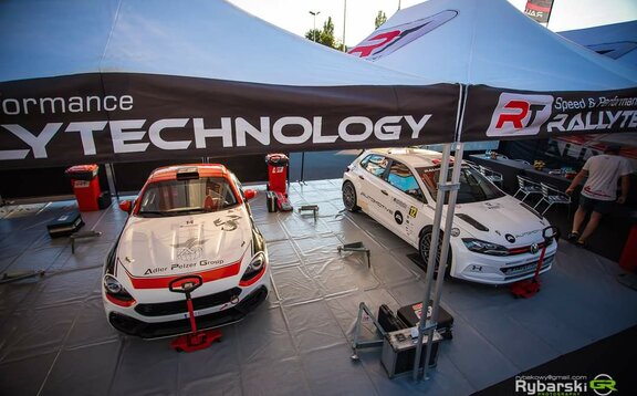 There are 2 racing cars under the RT Rally Technology racing tent. The folding tents serve as a workshop.