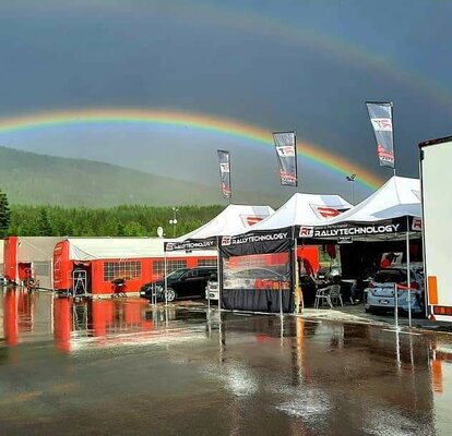 I gazebo racing della RT Rally Technology sono affiancate lungo il percorso. Sullo sfondo si vede un arcobaleno.