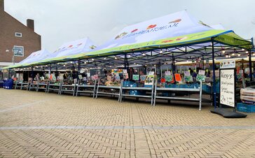 The market tents of Vitamientje.nl are next to each other. They have a canopy and are fully printed. Below them are the fruit stands.