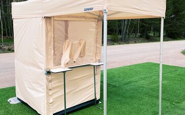 The Covid-19 test cabin in beige has been prepared for the rapid tests. You can see the cabin, the gaiters and the counter in front of it.