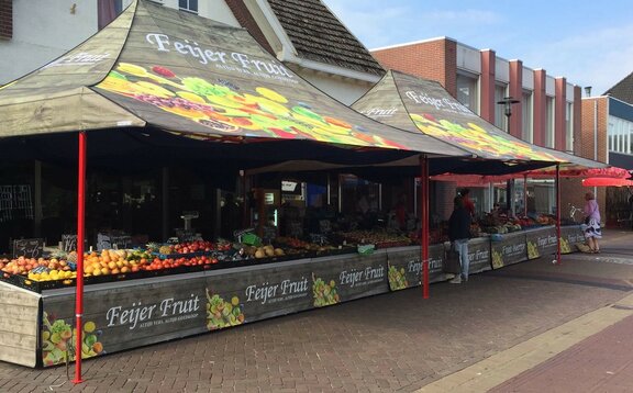 Das Marktzelt hat eine Größe von 6x3 m. Es ist vollflächig mit Obst bedruckt und hat eine rote Struktur.