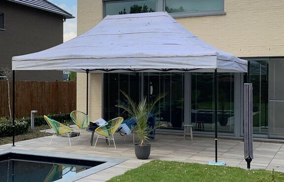 A garden tent with grey roof is standing on the terrace of a private house.