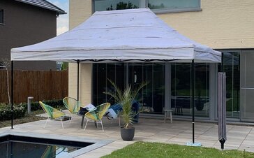 A garden tent with grey roof is standing on the terrace of a private house.