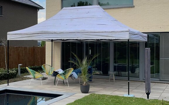 Un gazebo con tetto grigio è sulla terrazza di una casa privata.