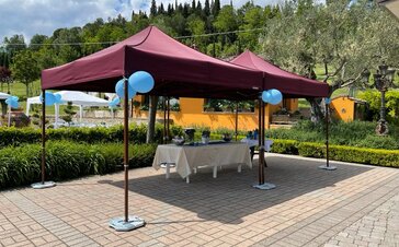 There is a garden tent and underneath it are some tables. The gazebos are stabilized with some weights.
