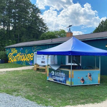 A Mastertent pavilion set up as a check-in station for kayak rentals. Designed with a blue roof and printed photos around the base panels.