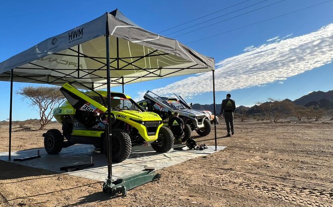 black and white racing gazebo at the Dacar Rally 2022 with two Arcane cars in the desert near the mountains