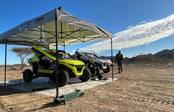 black and white racing gazebo at the Dacar Rally 2022 with two Arcane cars in the desert near the mountains