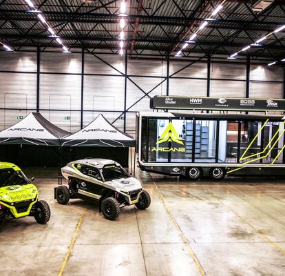 zwei schwarz-weiße Rennzelte bei der Rallye Dakar 2022 mit Rennwagen und Arcane-Van