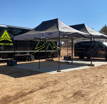 two black and white race gazebos at Dakar rally 2022 with black Arcane van in the sand