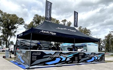 On the picture there is a black racing tent which was customised with a white logo and patterns. In addition, it has two personalised roof flags.