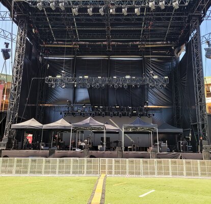 Auf einer Bühne vor einem Sting-Konzert stehen sieben 3x3 m große schwarze Faltzelte, die als Schutz für die technische Ausrüstung dienen.