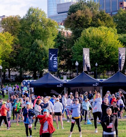 Su un prato ci sono tre gazebo pieghevoli neri di 3x3 m con bandiere sul tetto. I tetti, le bandiere e le pareti laterali sono personalizzati con il logo di Puma. 