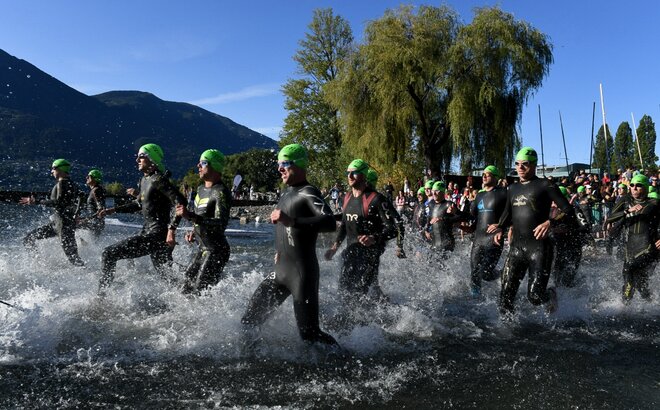 Athletes taking part in a triathlon run into the water.