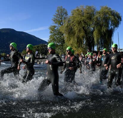 Athletes taking part in a triathlon run into the water.