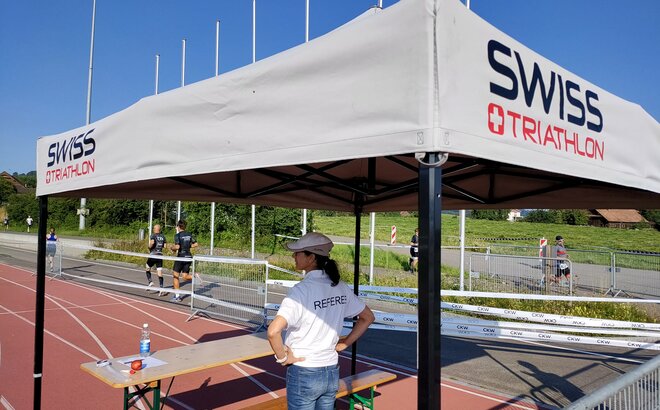 Eine Schiedsrichterin steht unter einem grauen 3x3 m Faltpavillon dessen Dach mit einem Logo personalisiert wurde.
