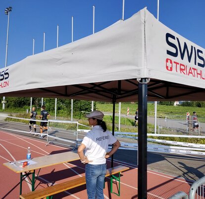 Eine Schiedsrichterin steht unter einem grauen 3x3 m Faltpavillon dessen Dach mit einem Logo personalisiert wurde.