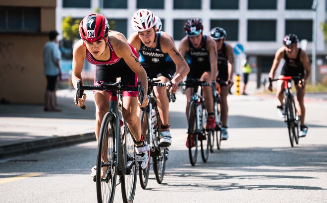 Auf dem Bild sind fünf Fahrradfahrer zu sehen, die an einem Triathlon teilnehmen.