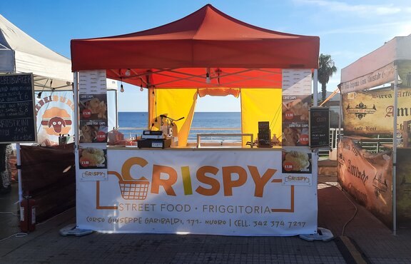 The picture shows a 3x3 m folding gazebo used as a street food vending tent. It has an orange roof, a counter, a sidewall with a door, and is personalized with a promotional print.