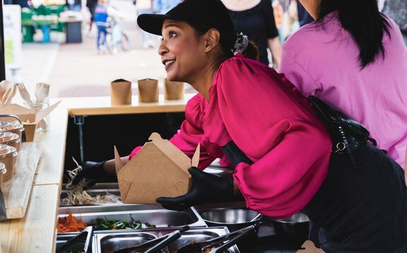 The picture shows a black 3x3 m folding gazebo, printed with the Pad Thai logo. The folding gazebo has a sidewall with a door and a half-height sidewall with a counter where the food is served.