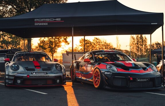 2 Porsche Experience Racing models side by side under a black 6x3 Oxford folding pavilion with straight panel and black aluminum frame in the background sunset