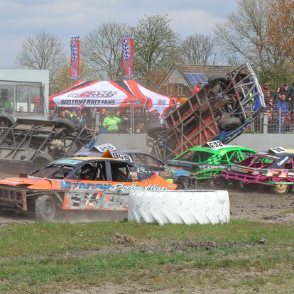 Une tente pliant blanc avec des drapeaux sur le toit est installé lors d'un événement automobile. Au premier plan, une course automobile est en cours.